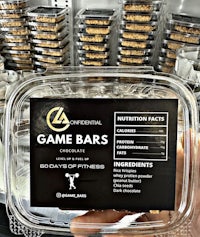 a person holding a container of game bars